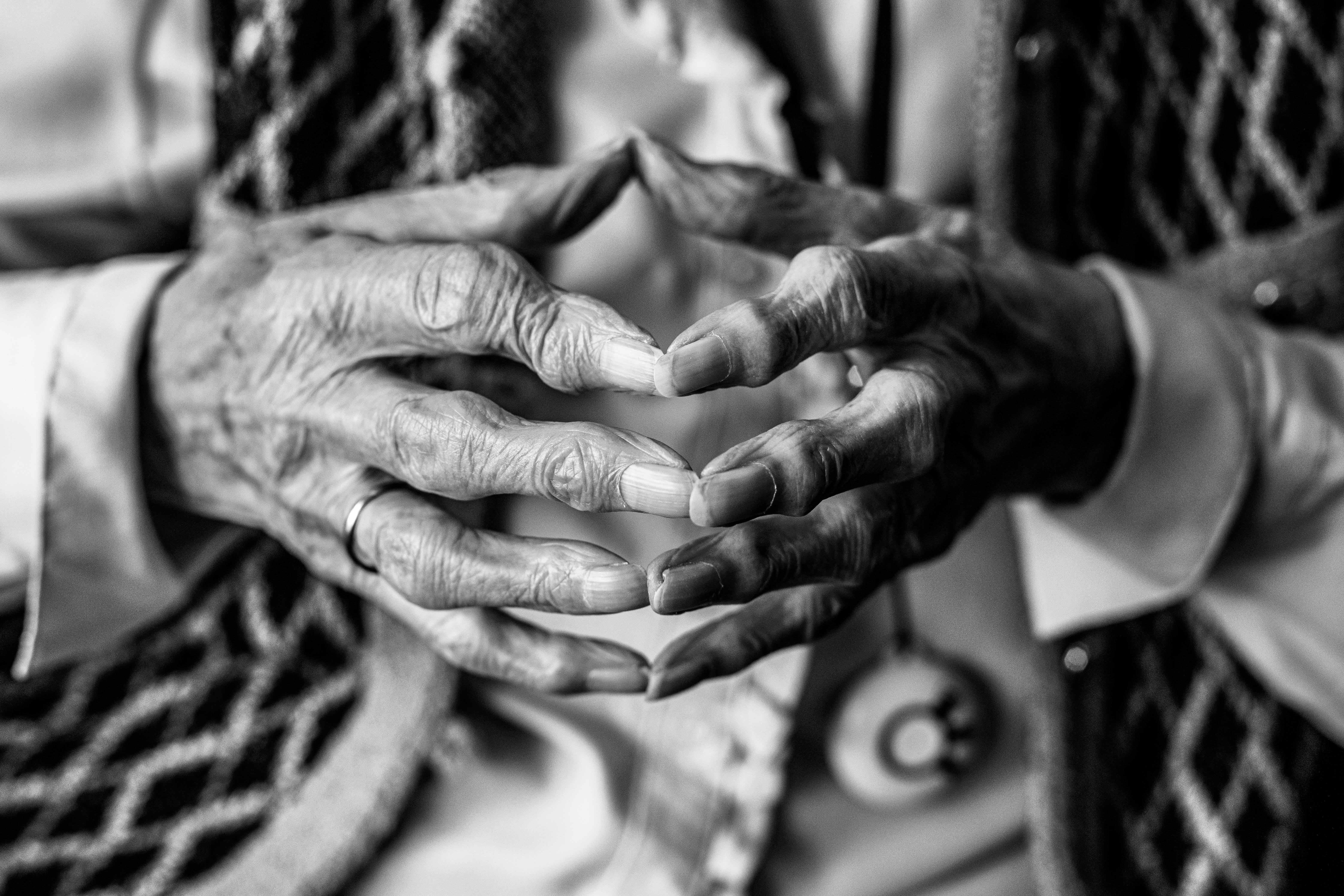 Een zwart-wit close-up van de handen van een oudere vrouw.