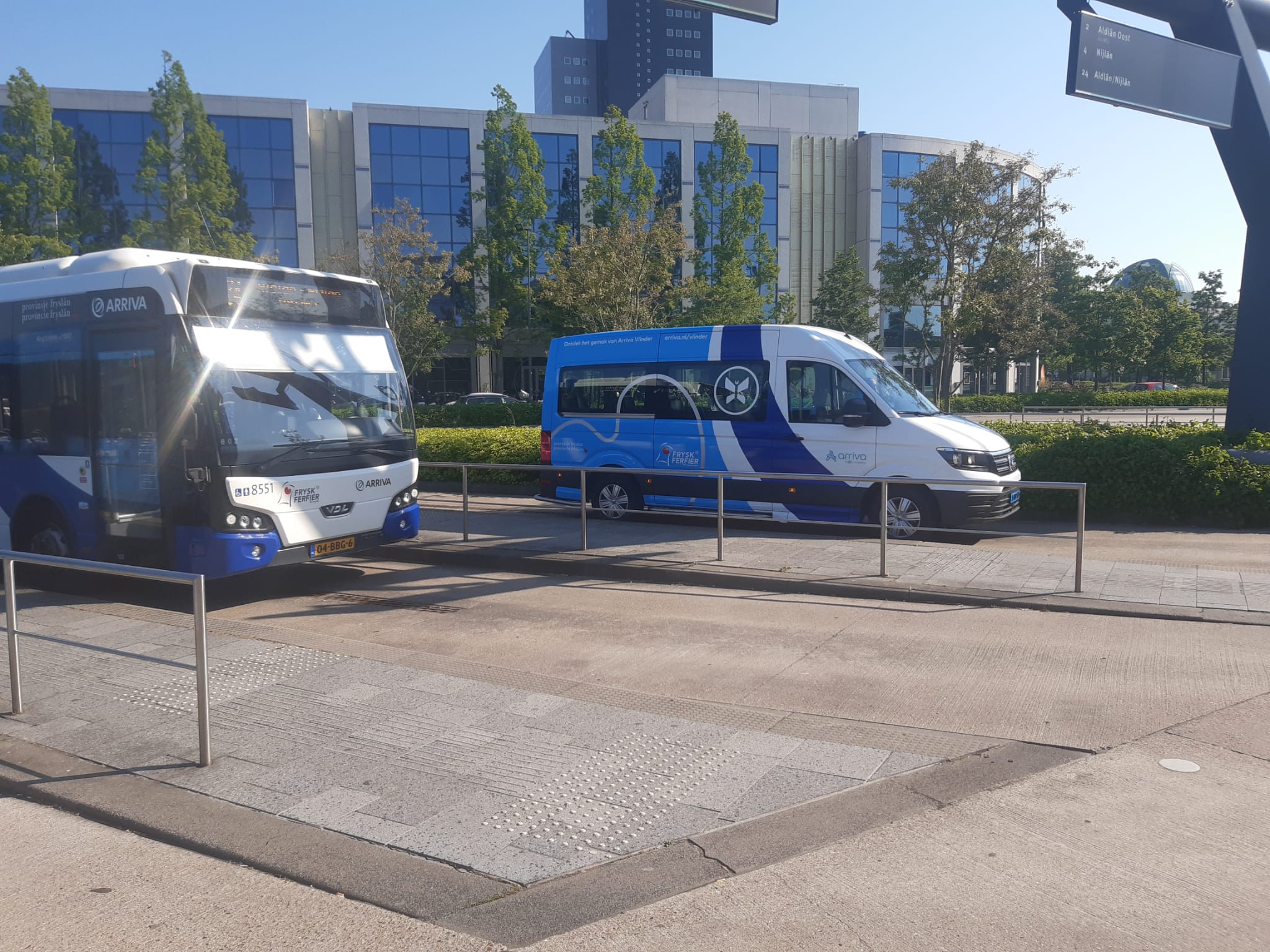 Een blauwwitte buurtbus van Arriva die Vlinder heet, staat geparkeerd bij de bushalte.