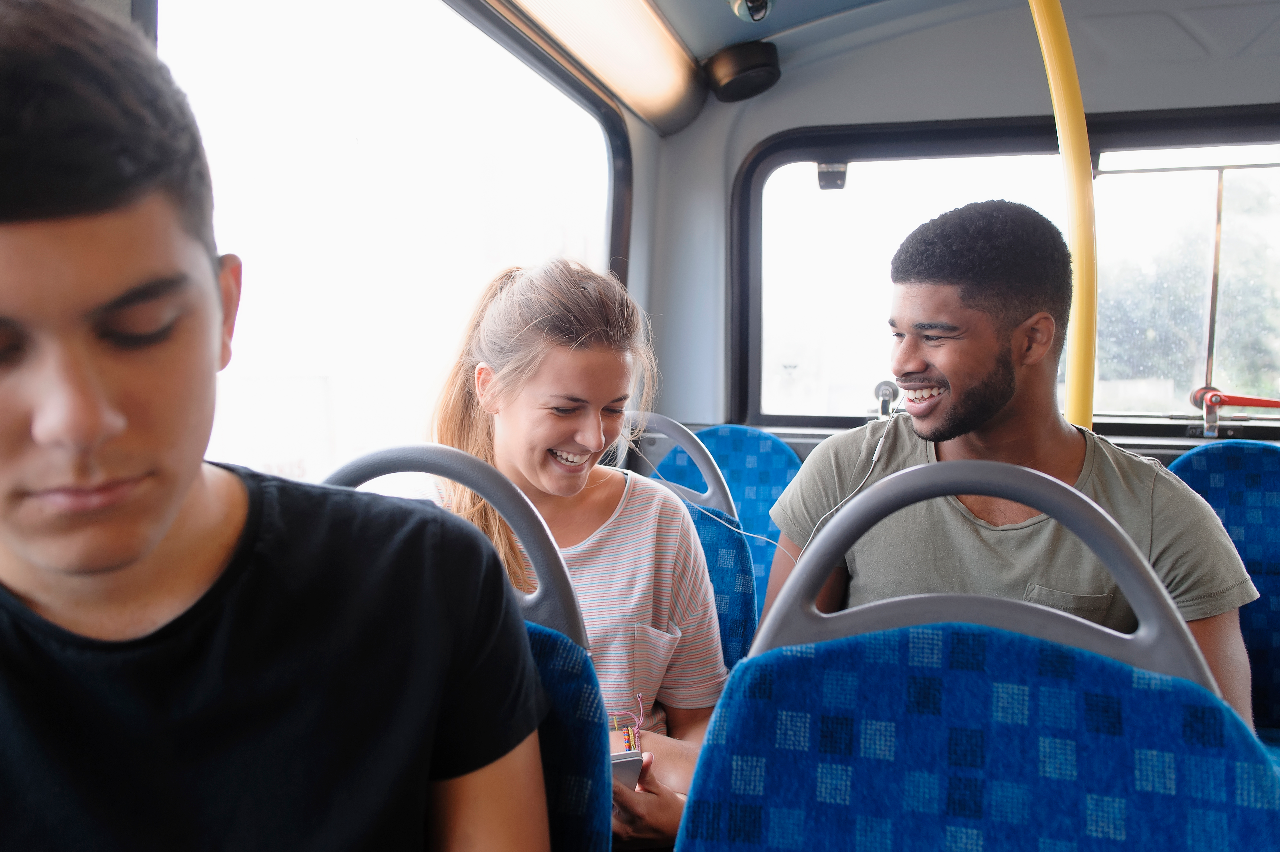 Een man en vrouw lachen samen terwijl ze naast elkaar in de bus zitten.