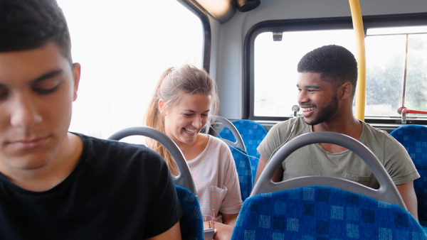 Een man en vrouw lachen samen terwijl ze naast elkaar in de bus zitten.