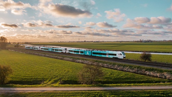 Een blauw-witte Arriva-trein rijdt over het spoor tussen weilanden met een ondergaande zon en een prachtige wolkenlucht. Een blauw-witte Arriva-trein rijdt over het spoor tussen weilanden met een ondergaande zon en een prachtige wolkenlucht.