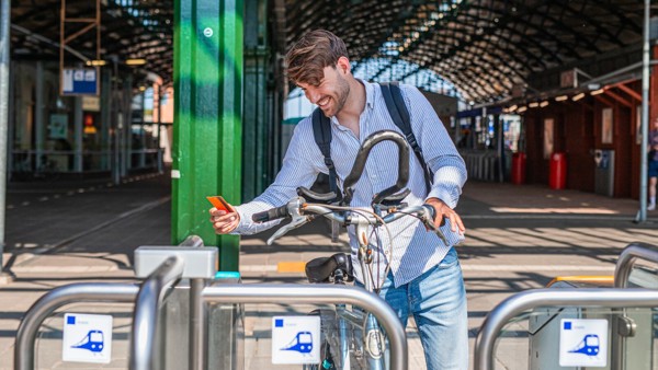 Man met fiets aan de hand checkt in met zijn betaalpas op een treinstation.