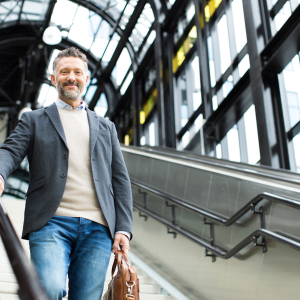 Man staat lachend op een trap in een treinstation. Man staat lachend op een trap in een treinstation.