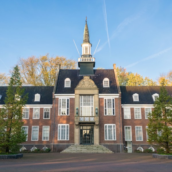 Statig gebouw met hoge ramen en klokkentoren in Alphen aan den Rijn op een zonnige dag. Symmetrisch ontwerp met een trap die leidt naar de indrukwekkende voordeur. Statig gebouw met hoge ramen en klokkentoren in Alphen aan den Rijn op een zonnige dag. Symmetrisch ontwerp met een trap die leidt naar de indrukwekkende voordeur.