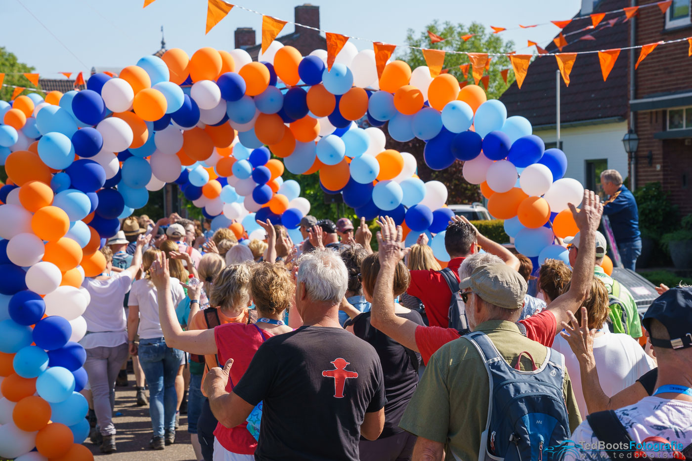 Deelnemers aan de Venloop lopen onder een ballonnenboog door.