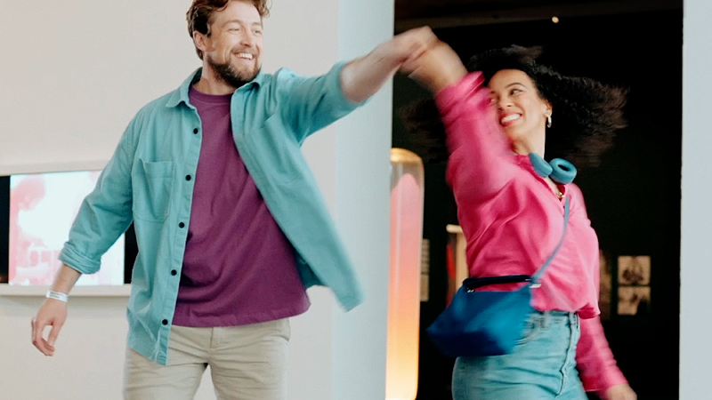 Een man en een vrouw in kleurige kleding dansen in een museum tijdens Museumday.