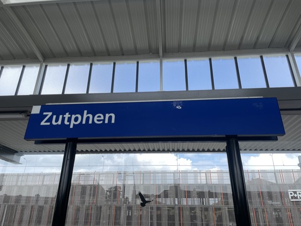 Donkerblauw plaatsnaambord met Zutphen erop op station Zutphen.