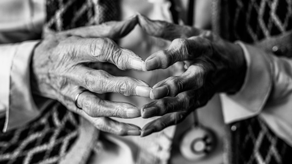 Een zwart-wit close-up van de handen van een oudere vrouw.