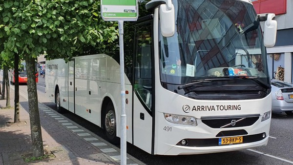 Witte Arriva Touringbus staat bij bushalte geparkeerd.