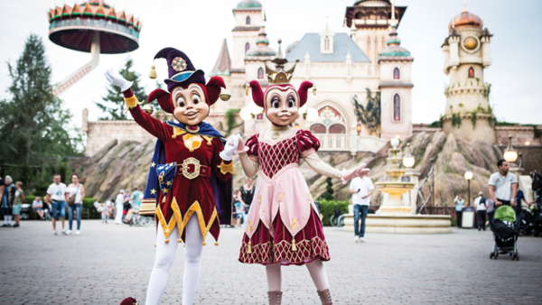 De nar Jokie en een vrouwelijke nar staan samen middenin de Efteling met onder andere de Pagode op de achtergrond.