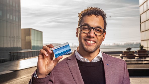 Een lachende man houdt een blauwe ov-chipkaart omhoog.