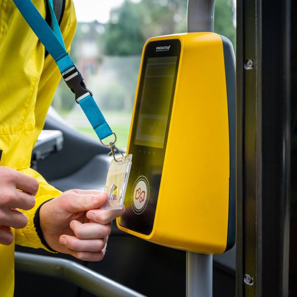 OV-chipkaart wordt door iemand in een gele jas voor de incheckpaal van een bus gehouden.