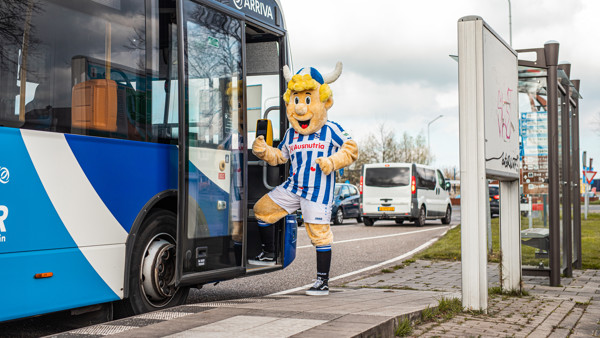 Iemand verkleed als de mascotte van sc Heerenveen, Heero, stapt in een blauwe Arriva-bus.