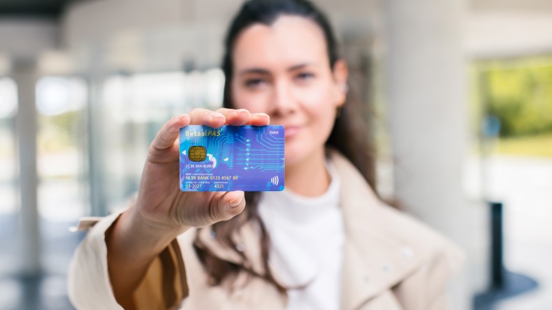 Reiziger houdt blauwe betaalpas richting de camera. Reiziger houdt blauwe betaalpas richting de camera.