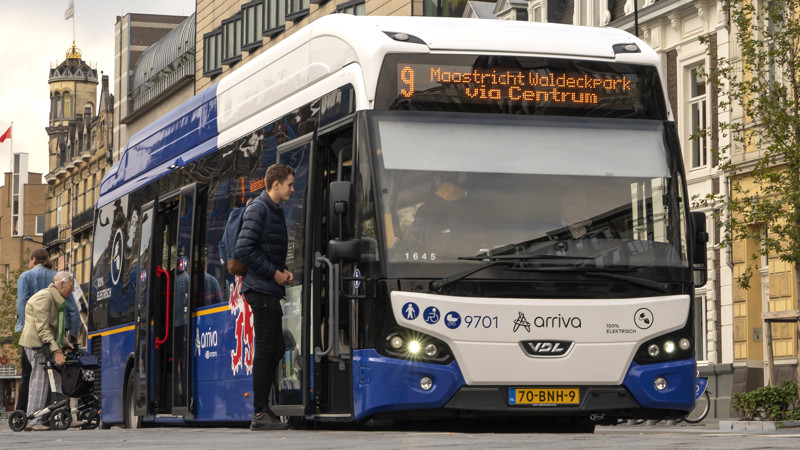 Limburgse bus laat passagiers binnen op de het busstation in Maastricht. Limburgse Arriva bus op het busstation in Maastricht. Voorin stapt een jongen in de bus en achterin gaat een oudere meneer met een rollator naar binnen om hun reis te beginnen.