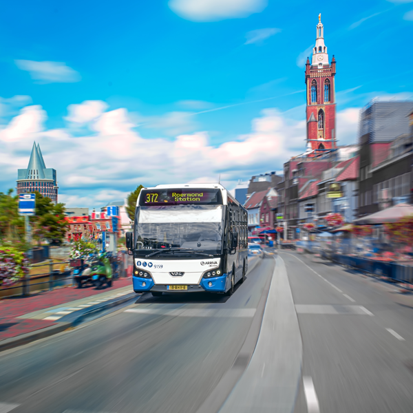 Blauwwitte bus van Arriva met '372 Roermond Station' rijdt door Roermond.
